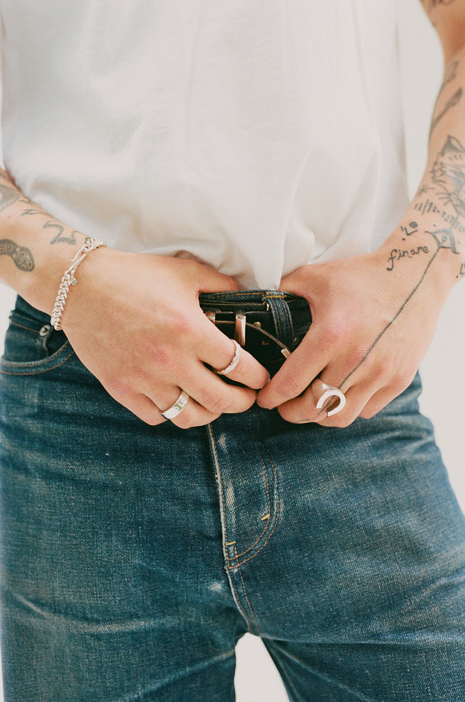 O.P Jewellery Skata Feather Ring in recycled 925 silver worn on a hand holding jeans and a belt.