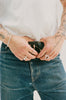 O.P Jewellery Skata Feather Ring in recycled 925 silver worn on a hand holding jeans and a belt.